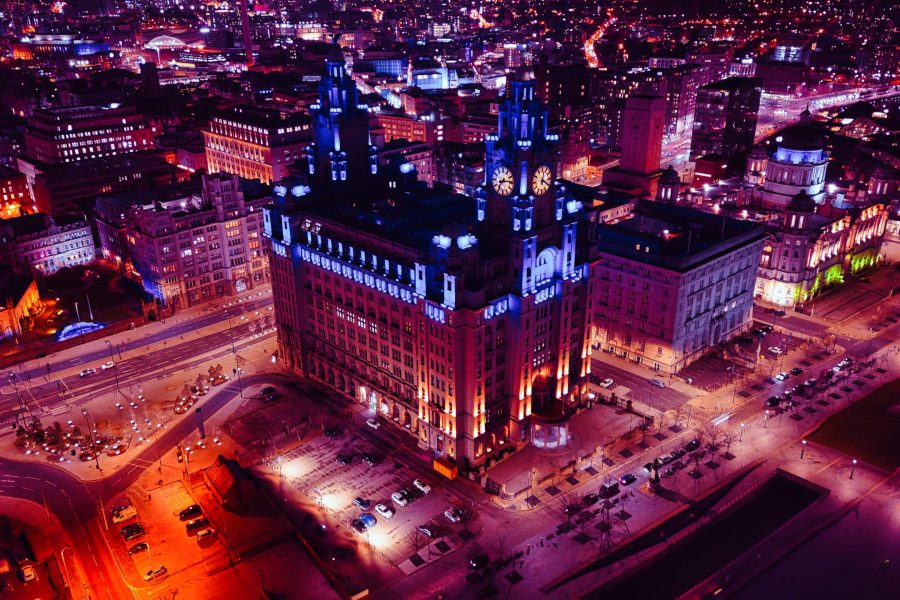 Aerial night view of an illuminated historic building in an urban cityscape in Liverpool, UK.