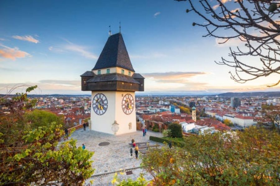 Classic panorama view of the historic city of Graz with famous Grazer Uhrturm clock tower in beautiful evening light at sunset, Styria, Austria